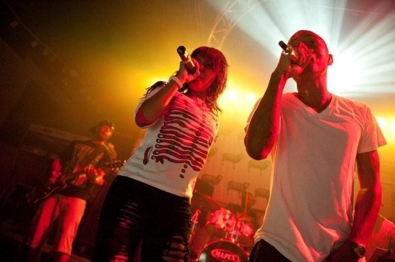 Pharrell Williams and Shay Haley performing together, bathed in warm stage light.